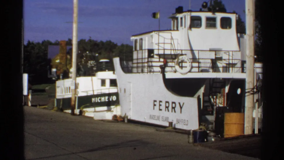 White ferry marked for Madeline Island and Bayfield docked at Bayfield, Wisconsin, with the boat NICHEVO alongside.