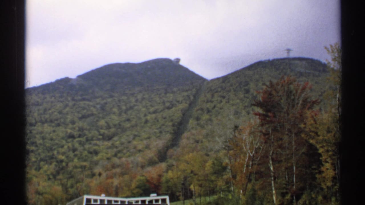 Mountain ridges with autumn trees and a partial building at the lower edge of the frame.