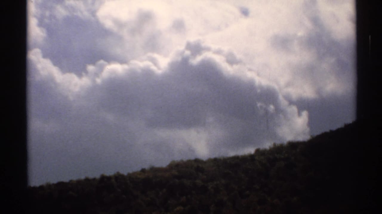 Clouds over a dark mountain ridge with 8mm frame borders visible.