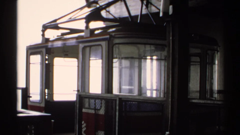 1971 Vermont 8mm frame showing a red and white cable car cabin beside station shadows and overhead support hardware.