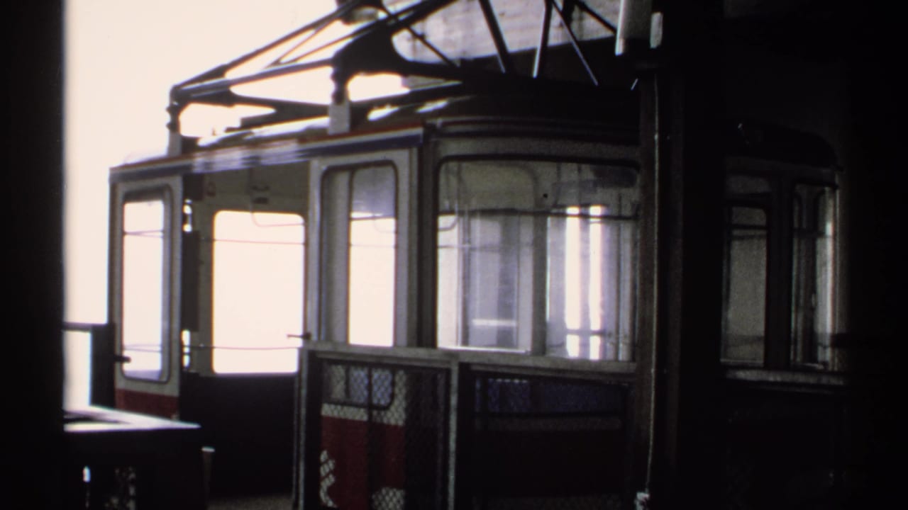 Cable car cabin framed by dark station structure and bright exterior light.