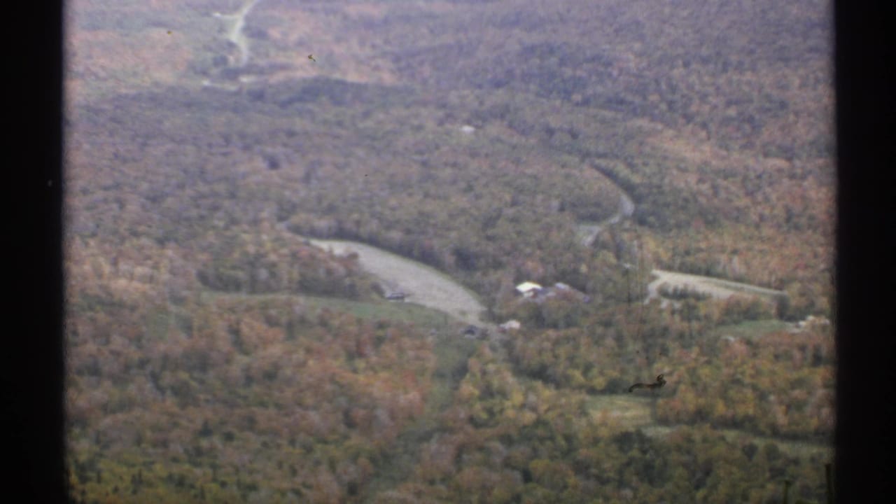 Aerial view of wooded valley with winding road and water bend.