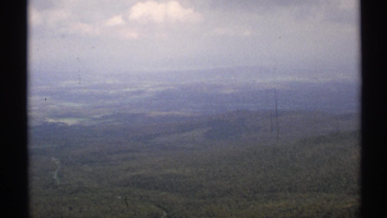 Hazy aerial view over forested Vermont hills with a distant valley and sky.