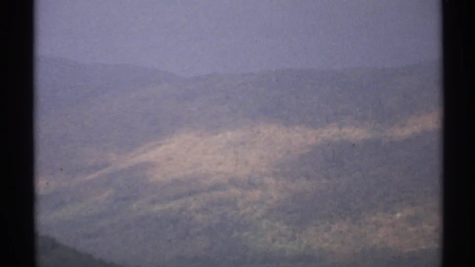 1971 Vermont 8mm frame showing a hazy aerial pass over a forested hillside with muted green and rust-colored tones.