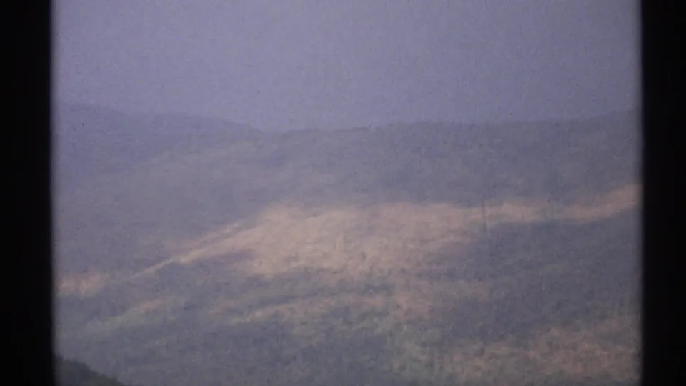 1971 Vermont 8mm frame showing hazy forested hills, muted autumn tones, and a faint utility line at the bottom edge.