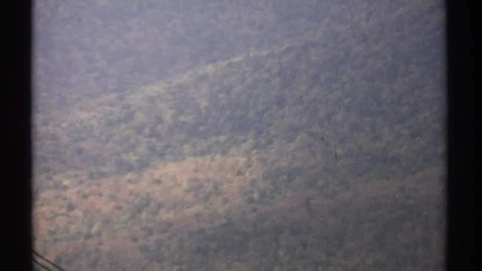 1971 Vermont home-movie view of wooded mountain terrain framed by dark tram-window edges.
