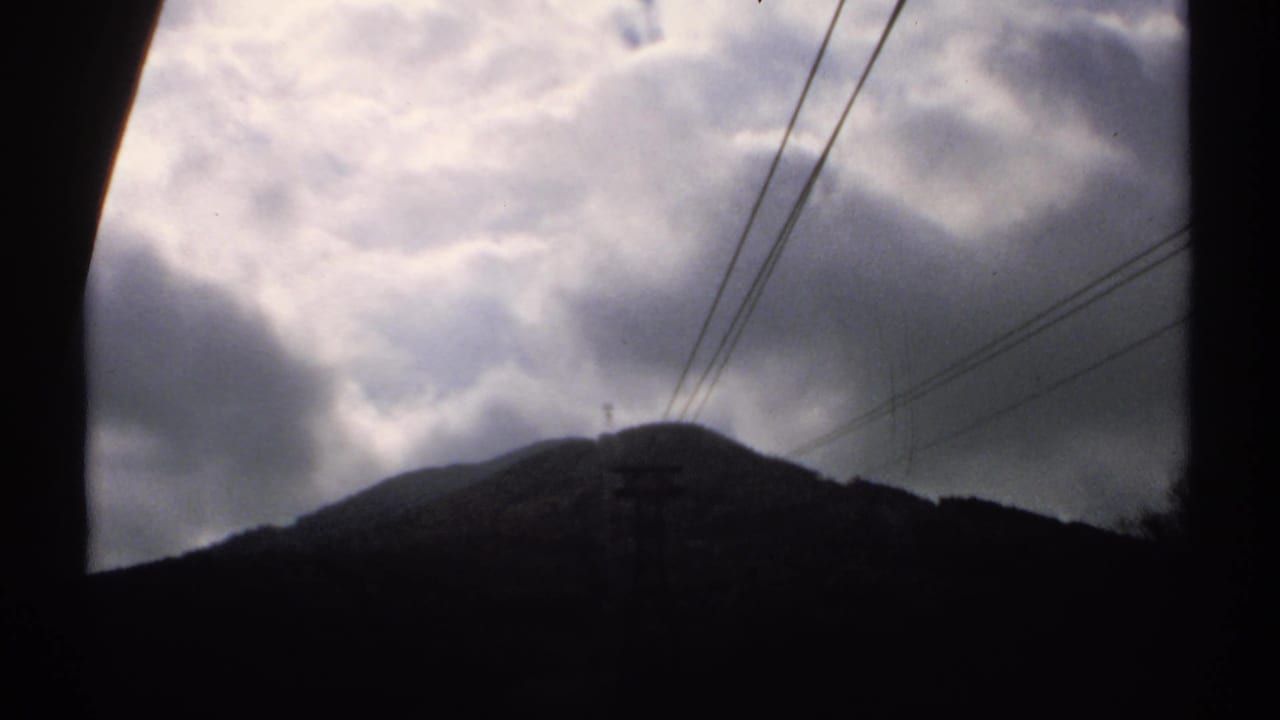 Clouded 1971 Vermont mountain view on 8mm film, with the ridge mostly in silhouette and power lines visible overhead.