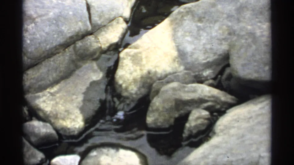 Close 1971 Wisconsin 8mm view of shallow water trickling among smooth rocks and pale stones.