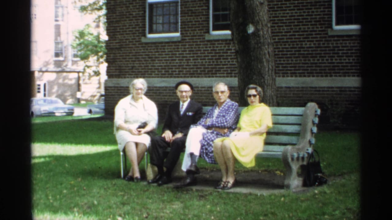 Four older adults remain seated on a bench, facing the camera.