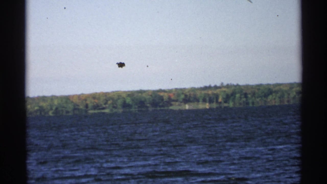 Dark blue lake water with wooded shoreline and cloudy sky.