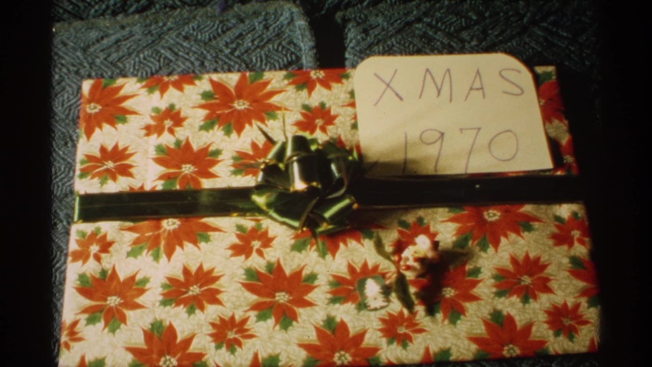 Wrapped Christmas package with red floral paper, green ribbon, and a handwritten Xmas 1970 card.