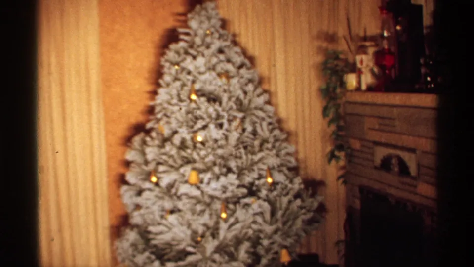 1971 Wisconsin home interior showing a flocked Christmas tree with gold ornaments, curtains, paneled walls, and a fireplace mantel.