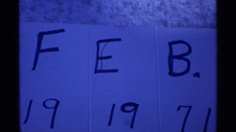 Another blue-tinted 8mm view of the handwritten FEB. 19 1971 card, with dark film borders visible.