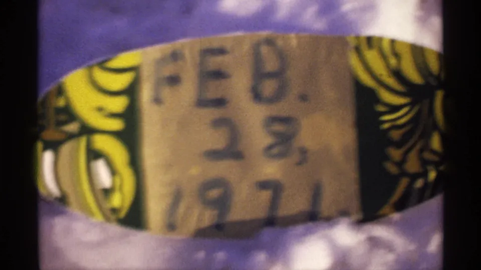 Soft 8mm close-up of a handwritten FEB. 28, 1971 label bordered by yellow and black decoration.