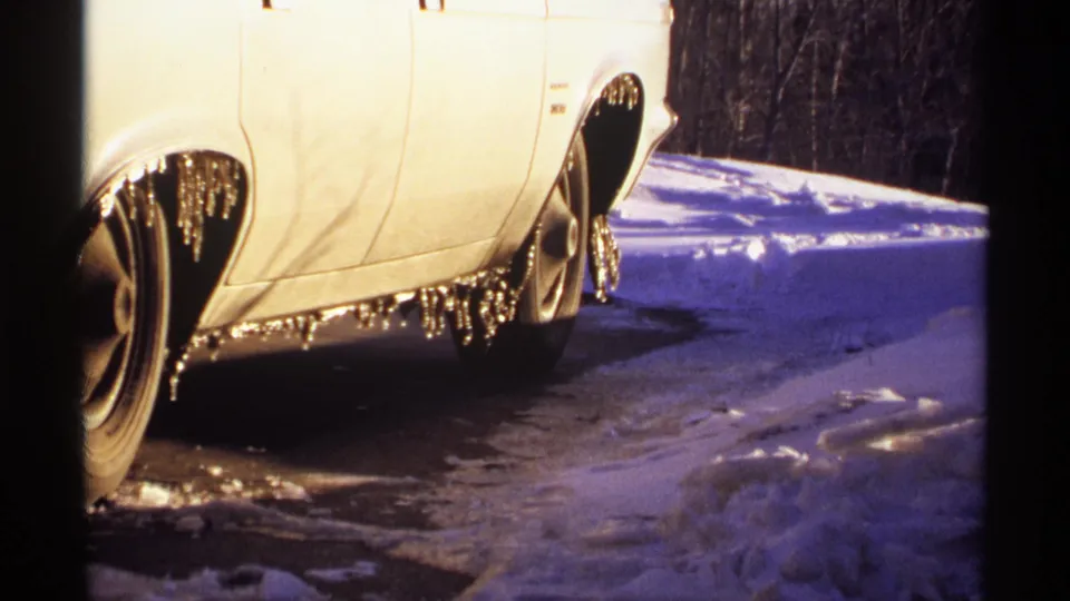 Side view of a white car with heavy icicle buildup along the undercarriage in a snowy 1971 Wisconsin scene.