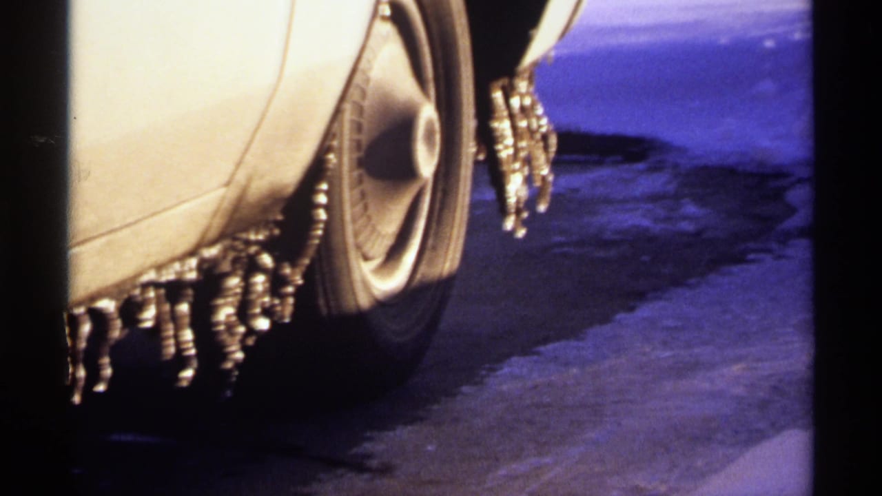 Close view of a car wheel and fender with icicles hanging from the body.