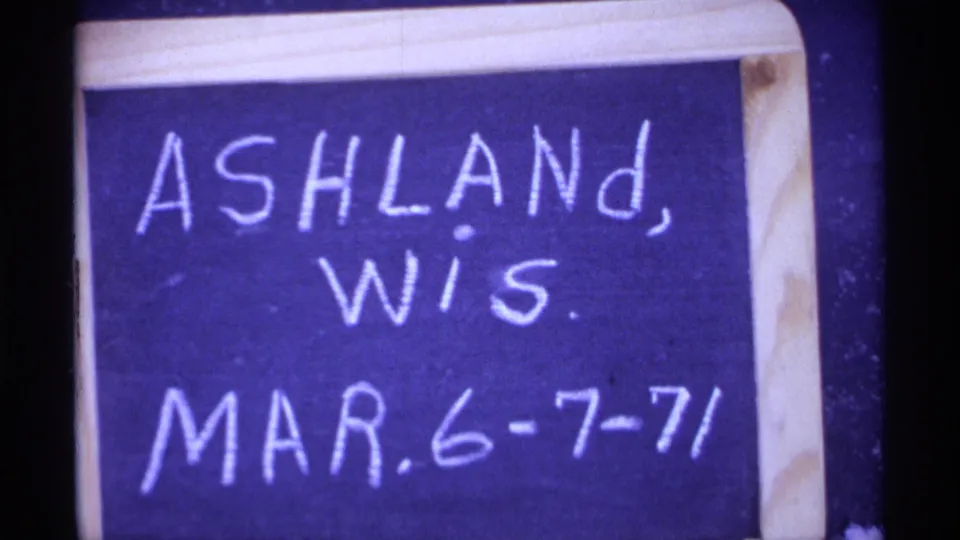 Close 8mm frame of a wood-framed board reading Ashland, Wis. and Mar. 6-7-71, confirming location and date.