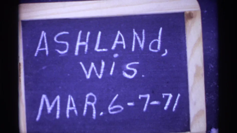 1971 8mm frame showing a handwritten Ashland, Wisconsin date title card on a small chalkboard.