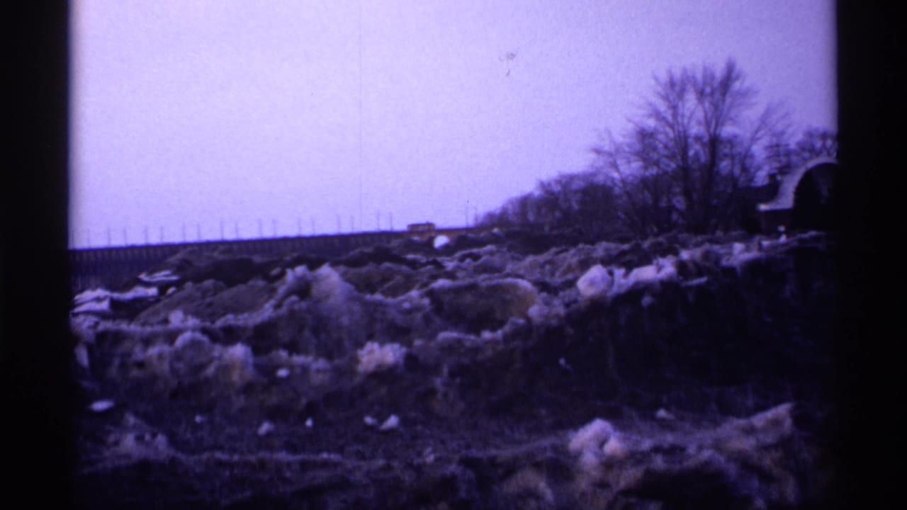 1971 Wisconsin 8mm frame showing a cold roadside area with snow-covered ground, bare trees, and dark film-edge framing.