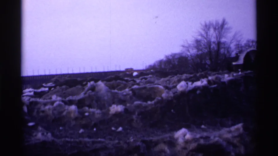 1971 Wisconsin 8mm frame showing a cold roadside area with snow-covered ground, bare trees, and dark film-edge framing.