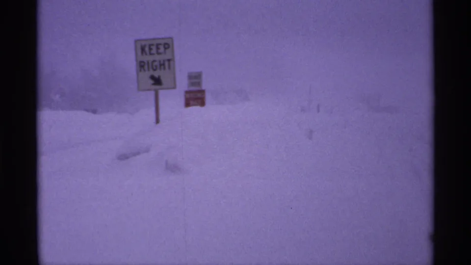 Snow-covered Ironwood-area roadside with a KEEP RIGHT traffic sign visible through falling snow.