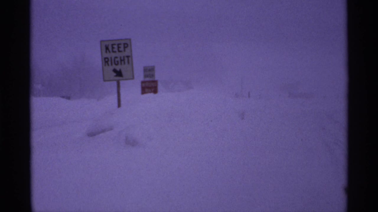 Snowbound Wisconsin roadside in 1971, with a KEEP RIGHT sign barely standing out against the blizzard haze.