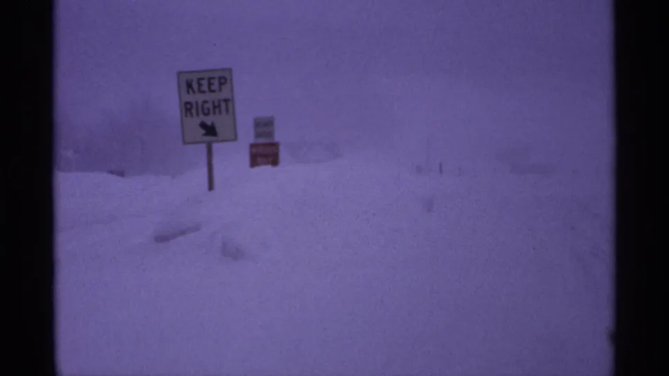 Snowbound Wisconsin roadside in 1971, with a KEEP RIGHT sign barely standing out against the blizzard haze.