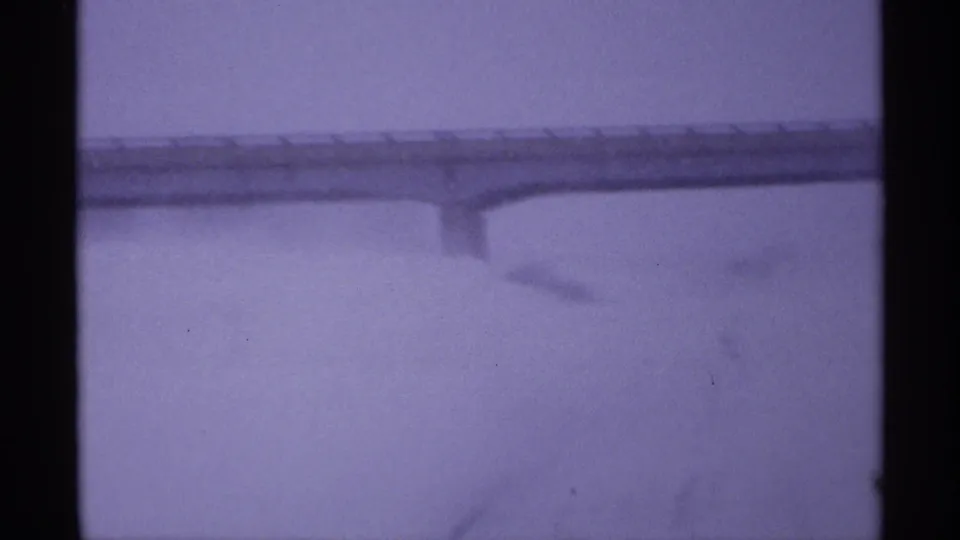 1971 Wisconsin 8mm frame showing a distant snow-covered overpass in low winter visibility with purple color shift.