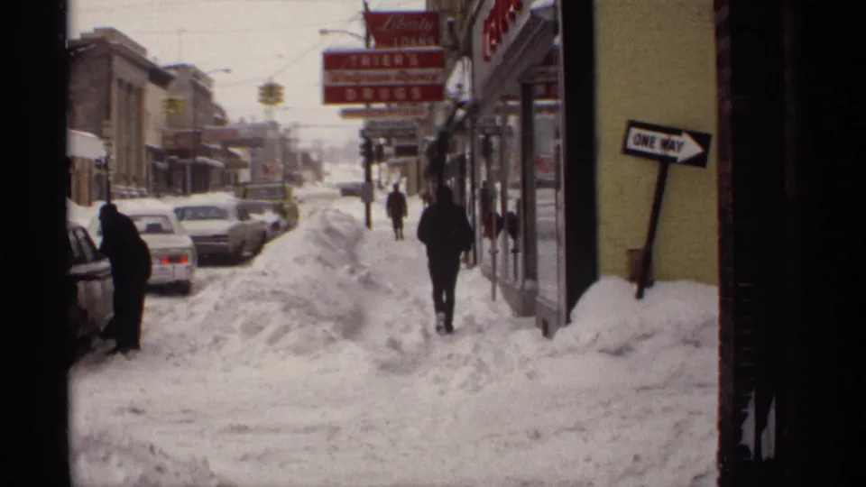 1971 Wisconsin downtown view showing pedestrians navigating piled snow beside classic cars and a visible Trier's drugstore sign.