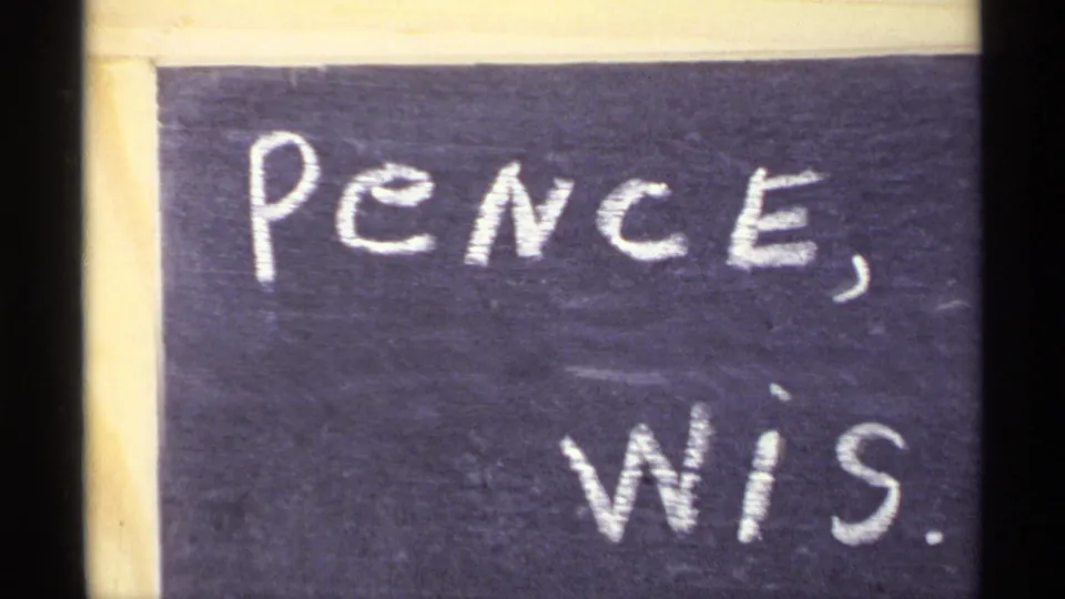 Close-up 8mm frame of a chalkboard place marker reading Pence, Wis., supported by the clip metadata as Wisconsin in 1971.