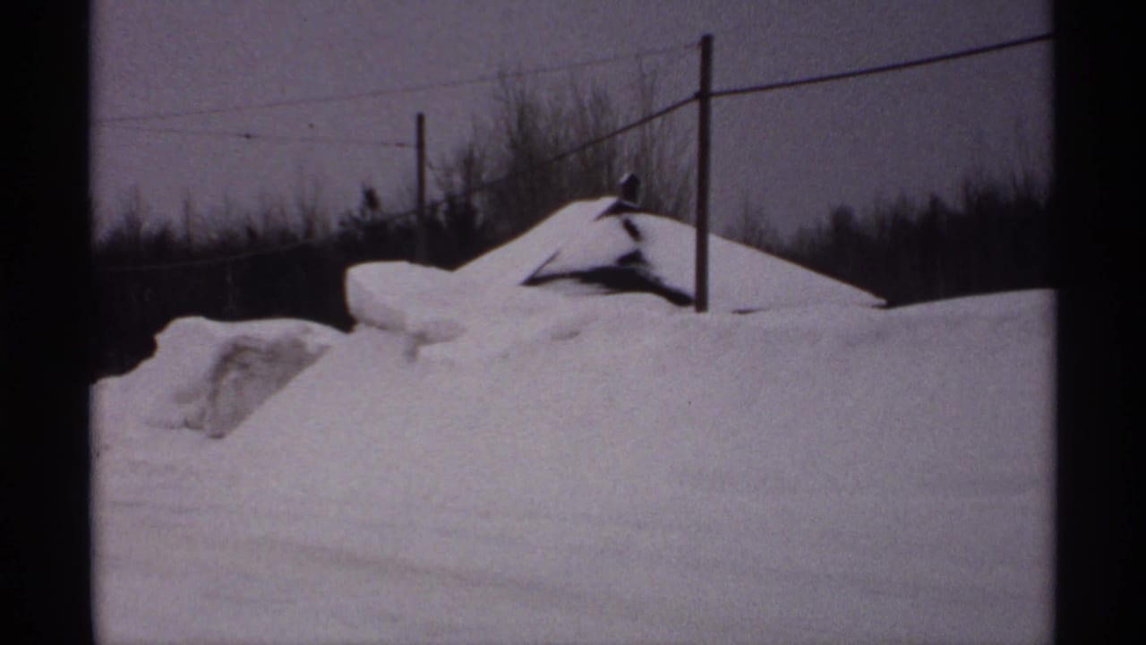 Deep snowbanks beside a rural road with utility poles and bare trees.