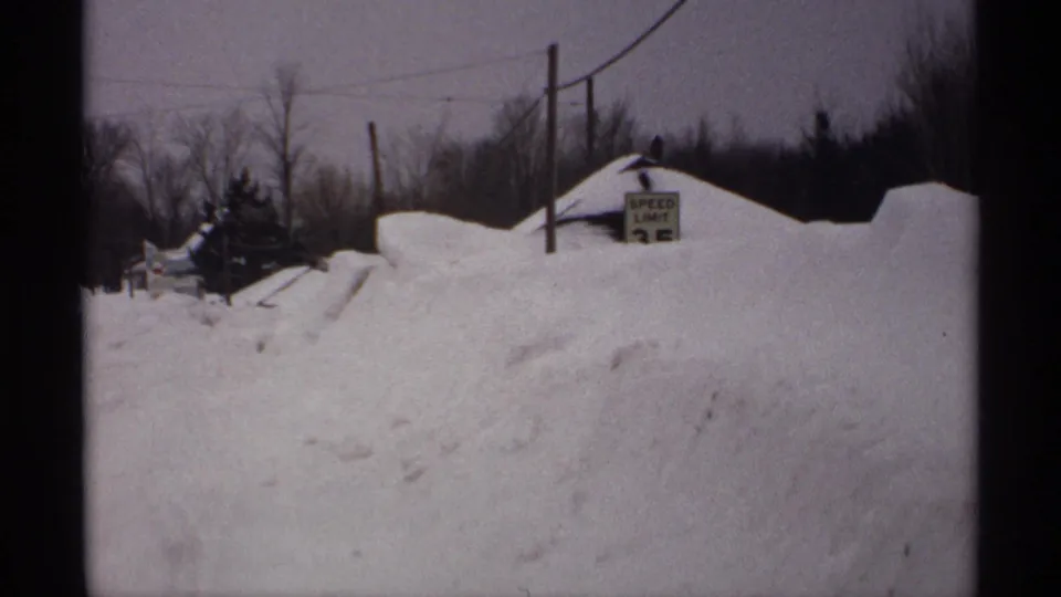Rural Wisconsin snow scene from 1971 showing a SPEED LIMIT 25 sign rising from deep drifts near utility lines.