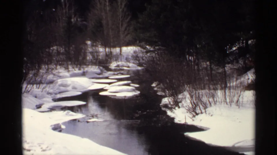 1971 Wisconsin 8mm view of a winter stream winding between snow-covered banks and rounded ice floes.