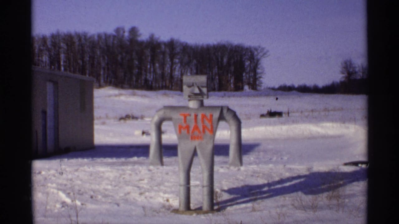 Snowy view of the tin man sculpture with a small building at left.