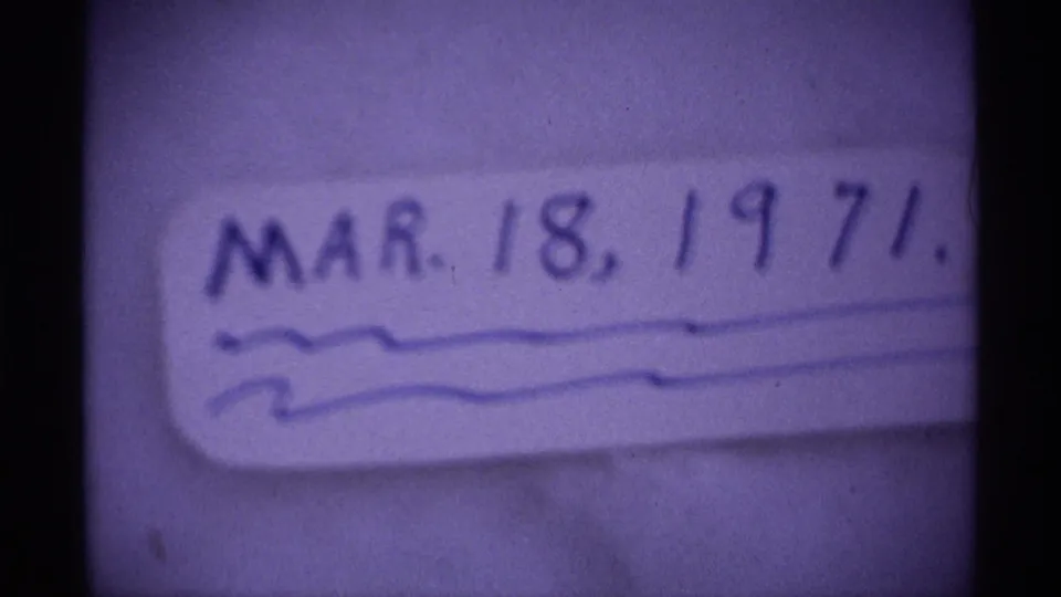 Close-up 8mm frame showing a handwritten date label, MAR. 18, 1971, with soft focus and visible film texture.