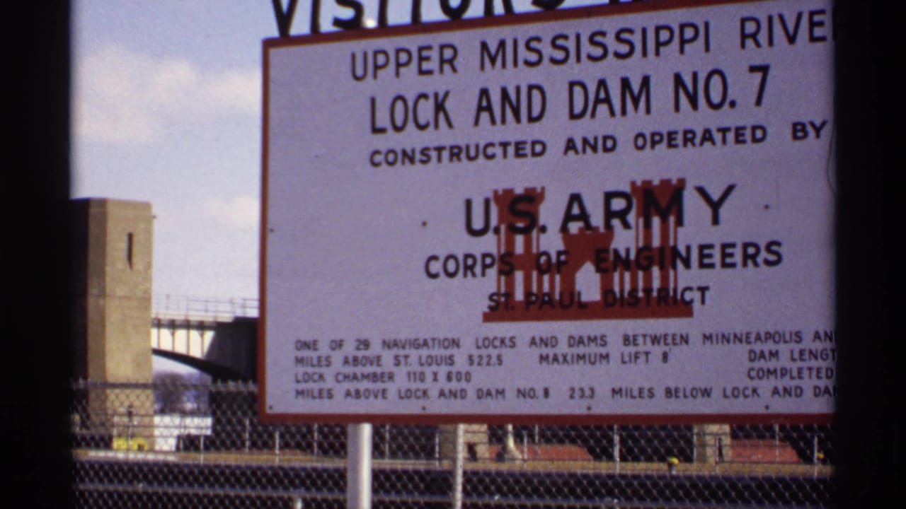 Visitor sign for Upper Mississippi River Lock and Dam No. 7 beside dam structures.