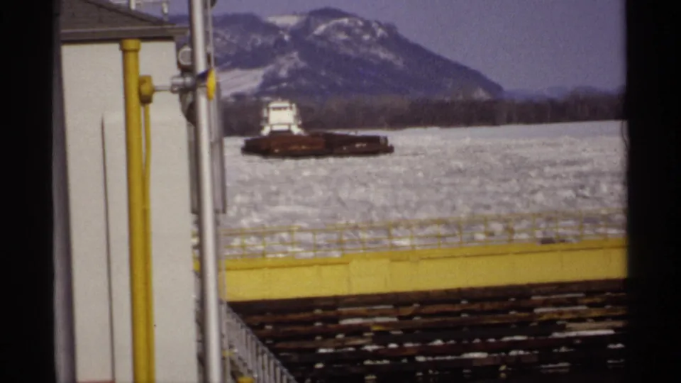 Final frame shows the distant barge across broken ice, with yellow railings and vertical pipes in the foreground and mountains behind.