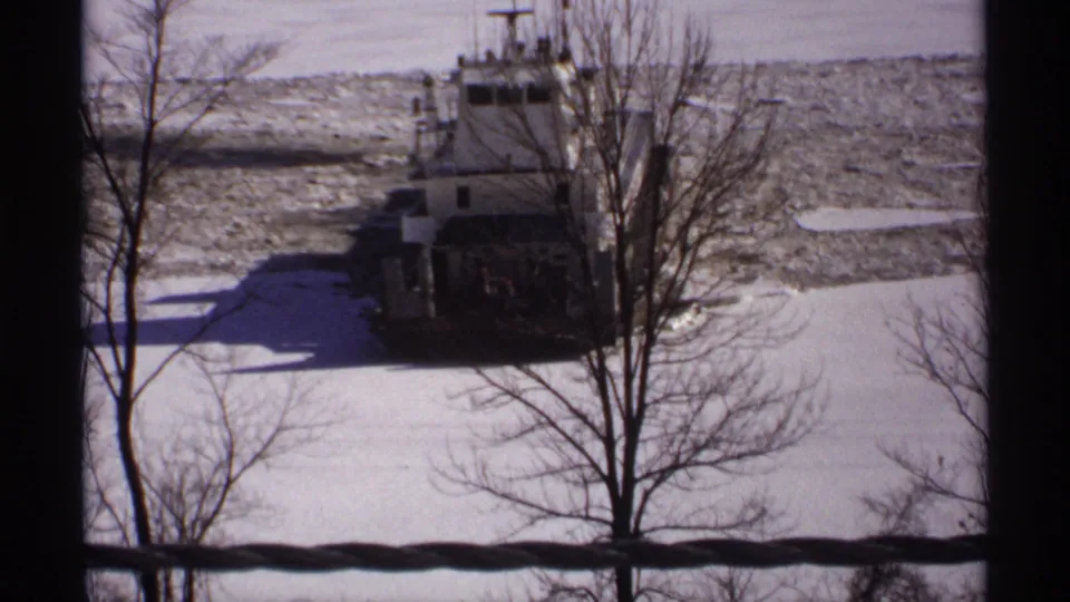 1971 Wisconsin 8mm view of a tugboat in icy water, seen from an elevated interior or window-side vantage.