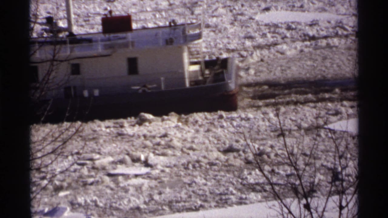 White tugboat close to the frame edge amid rough ice on the river.