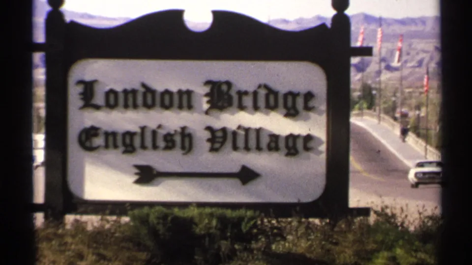 Roadside London Bridge English Village sign in Arizona, with an arrow pointing right and desert hills beyond.