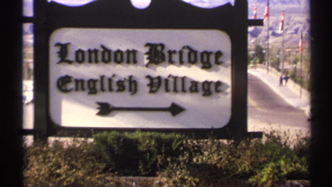 London Bridge English Village sign with black lettering and an arrow beside a road.