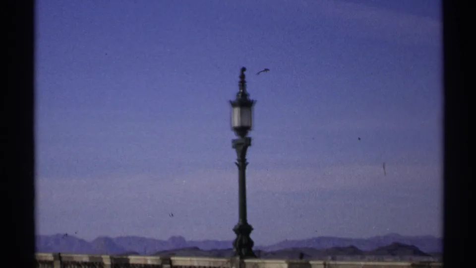 An ornate lamp remains framed against the Arizona sky, with a stone balustrade and desert ridgeline visible below.