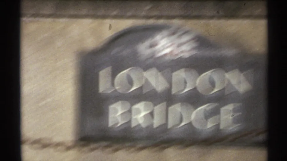 1972 Arizona home-movie frame showing motion-blurred London Bridge lettering and crest during a handheld move.