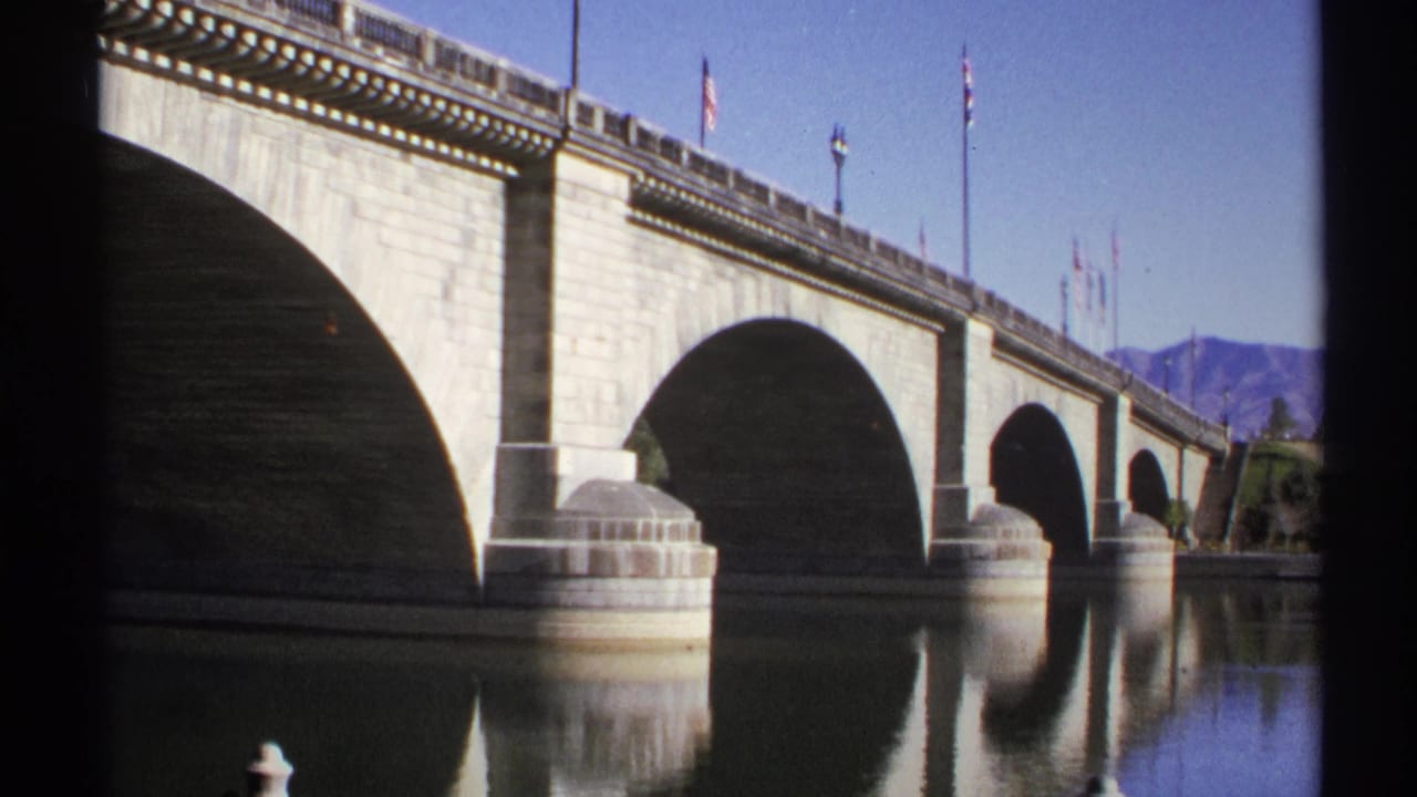 1972 Arizona home-movie view of the bridge arches, flagpoles, still river reflections, and distant desert mountains.