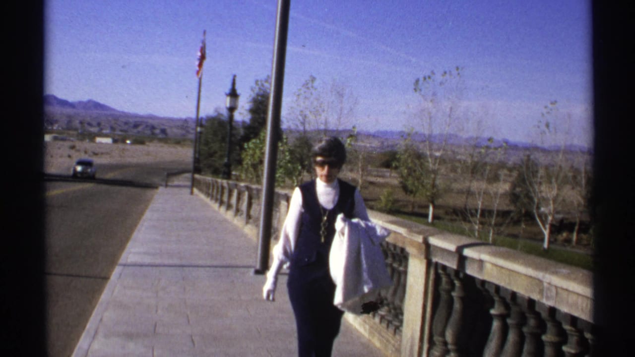 Woman walking on a paved bridge walkway beside a stone balustrade.