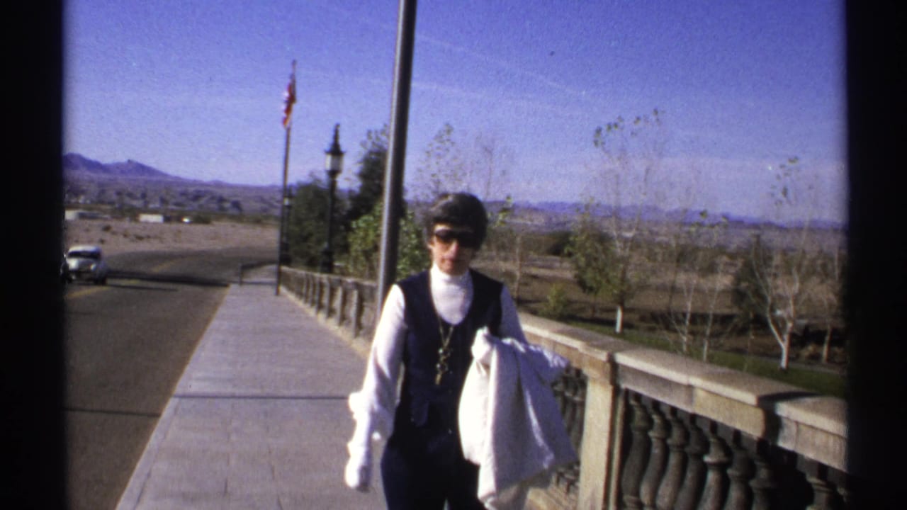 Woman in sunglasses walks closer along the bridge walkway.