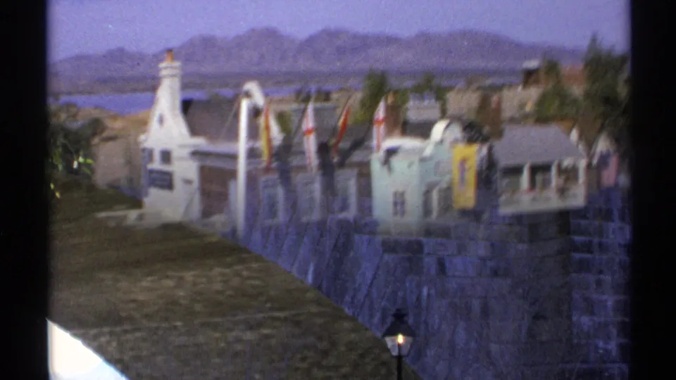 1972 Arizona 8mm frame with motion blur as the camera shifts from miniature town facades to a stone bridge display.