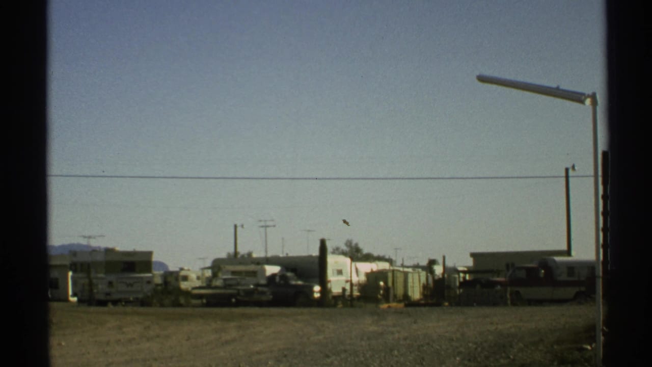 Gravel lot with parked RVs and trailers under a clear sky.