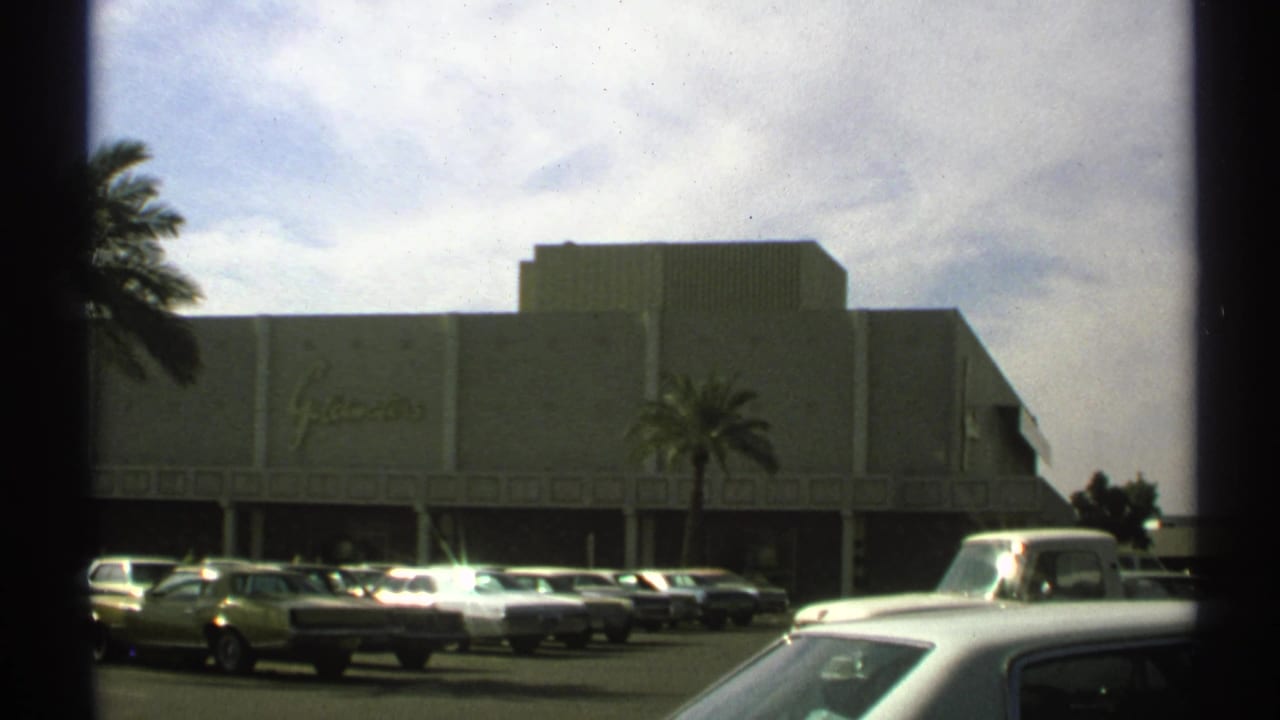 Goldwaters department-store exterior seen across a parking lot with cars and palm trees.