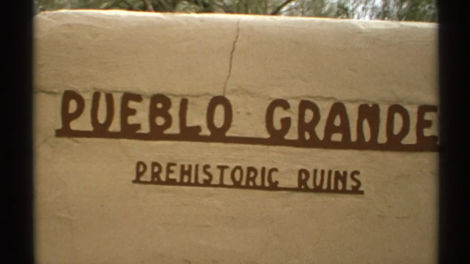 1972 Arizona 8mm close-up of a stucco wall marked PUEBLO GRANDE PREHISTORIC RUINS in dark brown painted text.